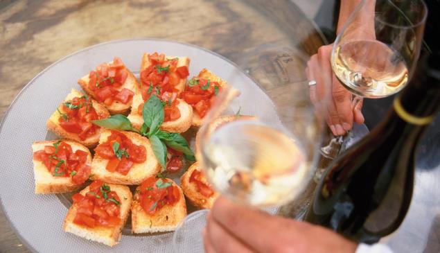 A plate with Bruschettas and two glasses with white wine